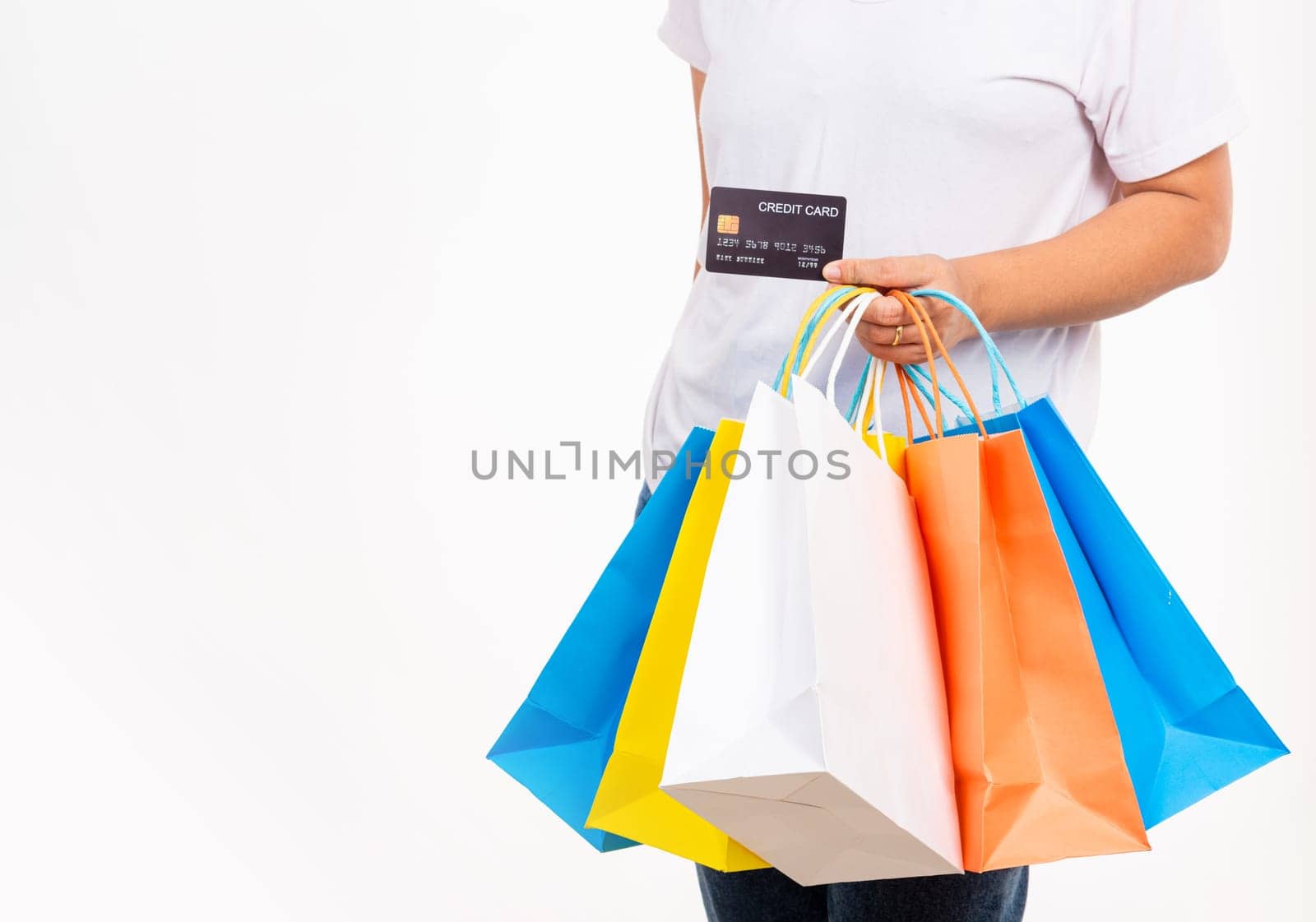 Happy woman hand holding shopping bags multicolor and credit card for shopping online, young female hold many packets within arms isolated on white background, Black Friday sale concept