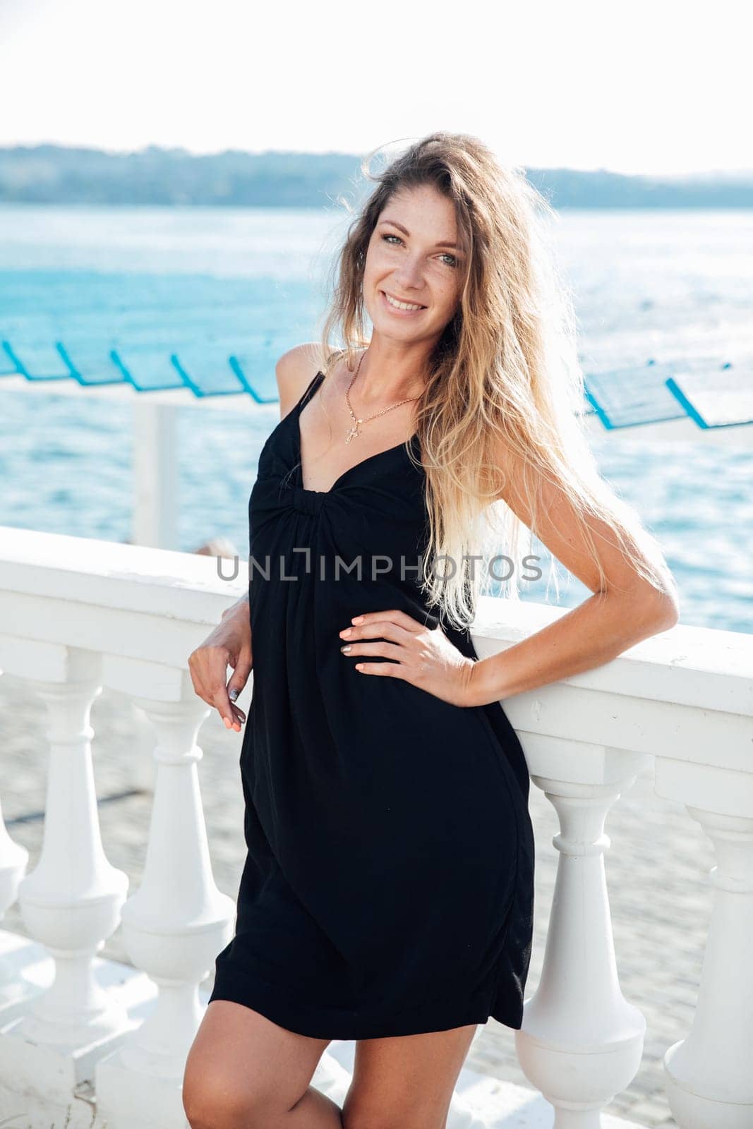 beautiful woman stands near the white railings on a walk travel vacation