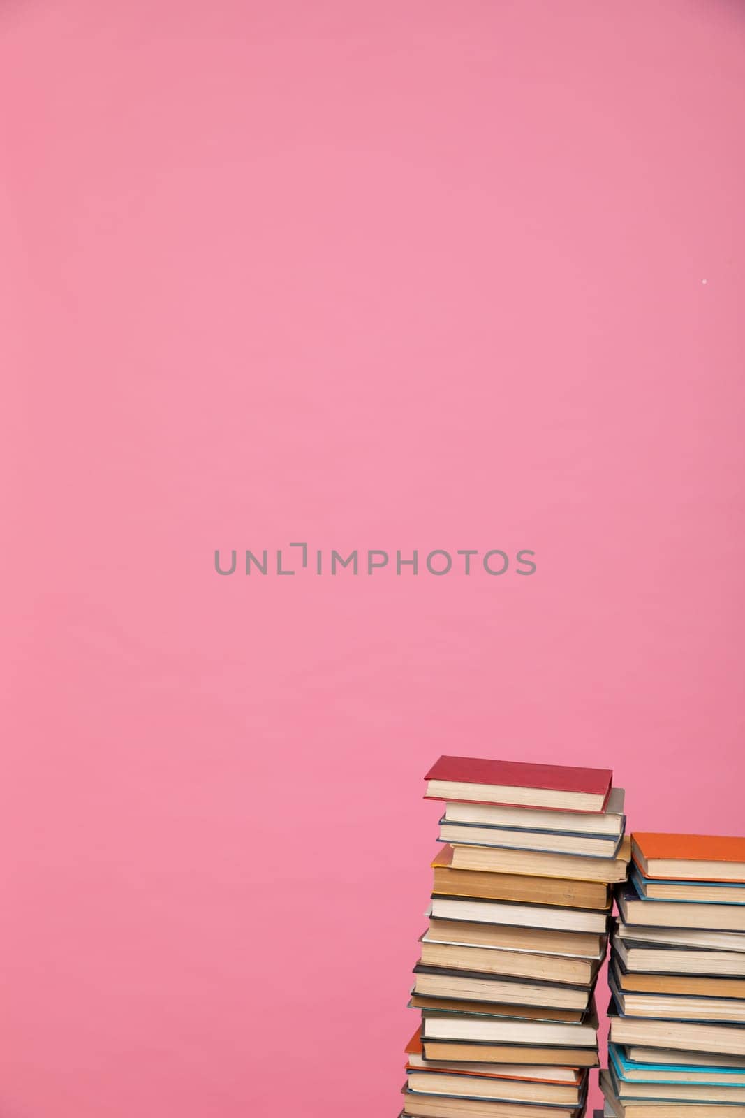 science education stack of books on pink background literacy training by Simakov