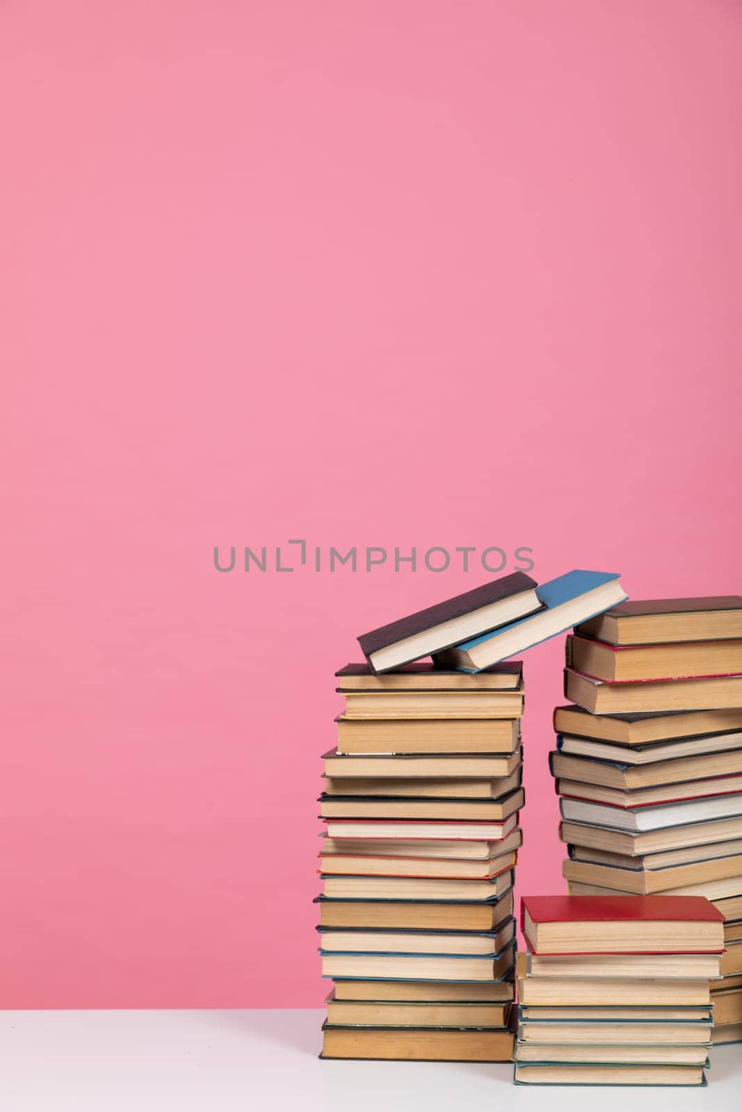 science education stack of books on pink background literacy training by Simakov