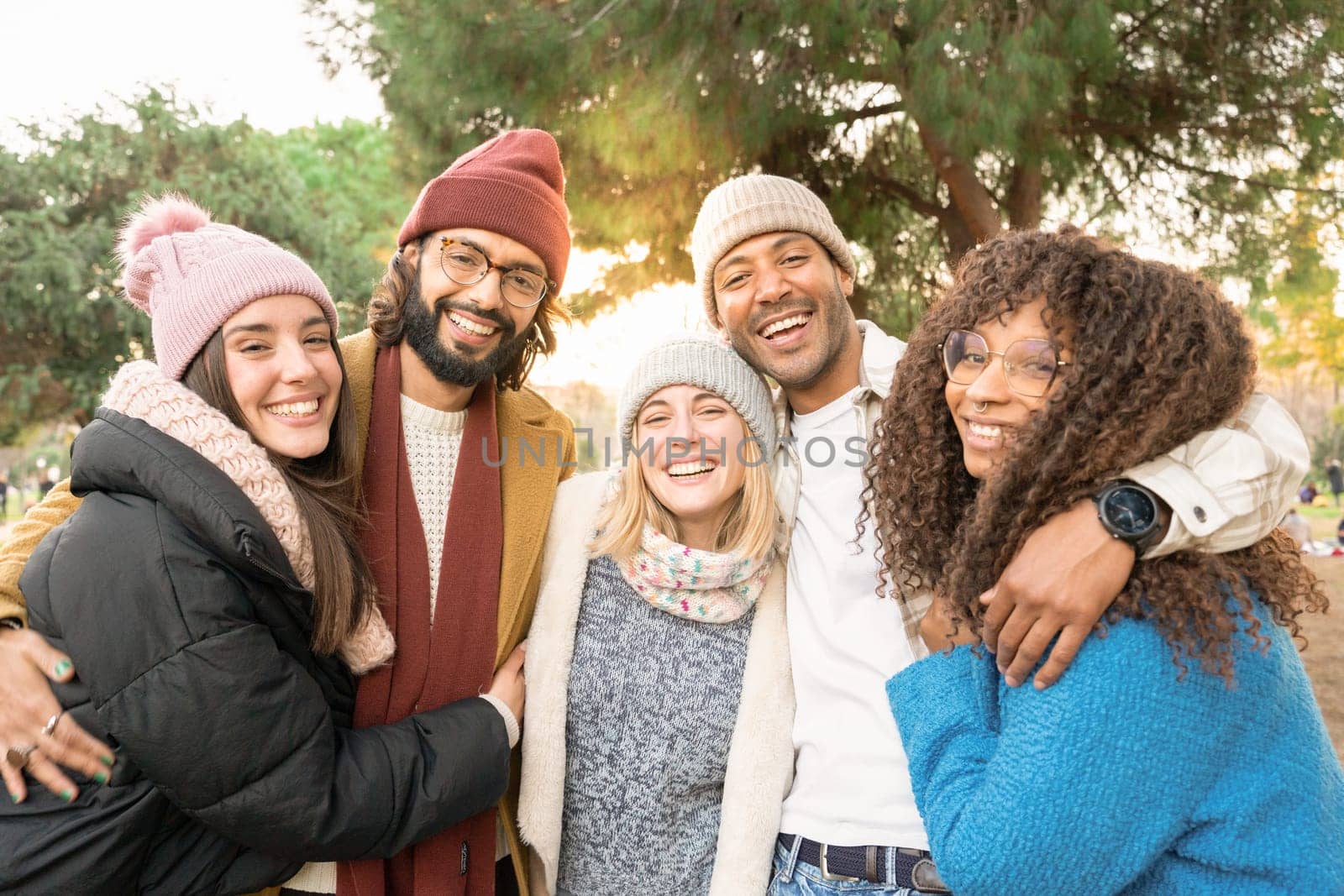 Group of friends looking at camera smiling outdoors in a park in winter. High quality photo