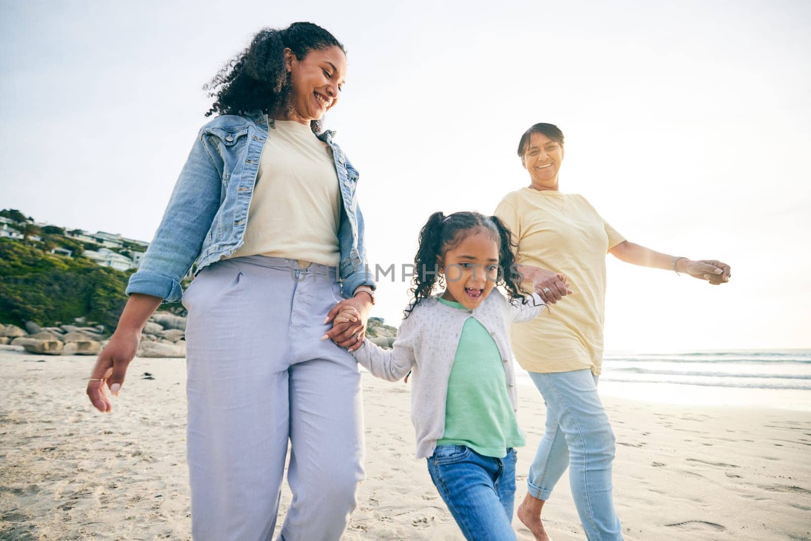 Happy, family and holding hands at the beach while walking for freedom, travel and holiday by the sea. Smile, care and a mother, grandmother and child at the ocean for bonding, vacation or together by YuriArcurs