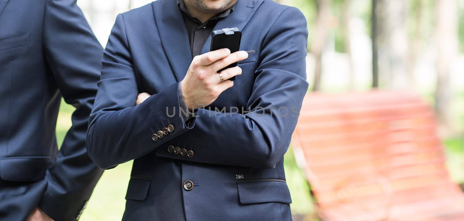Young urban professional man using smart phone. Businessman holding mobile smartphone using app texting sms message by Satura86
