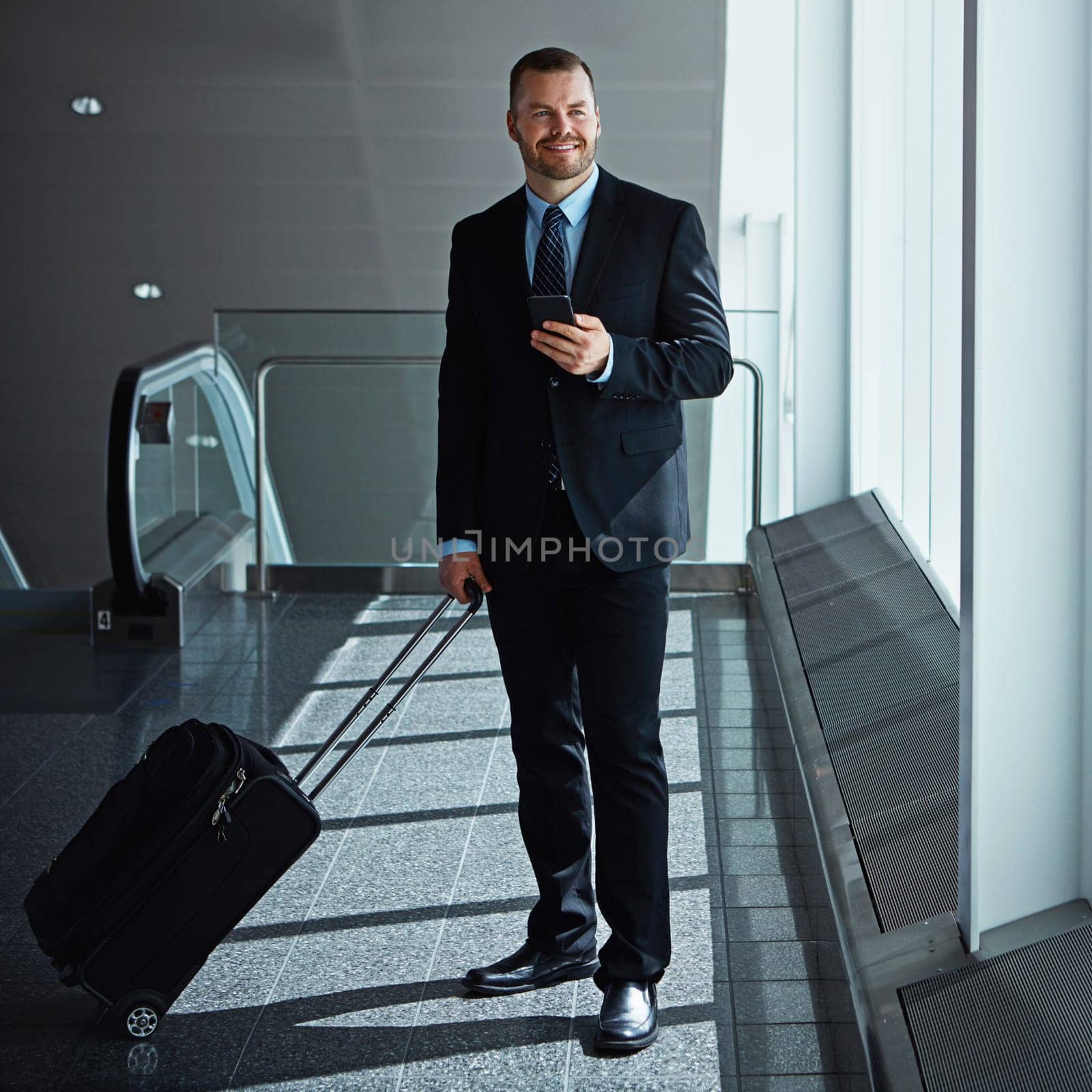 Social media, thinking or business man in airport with phone, luggage or suitcase for travel booking. Happy, entrepreneur or corporate worker texting to chat on mobile app on international flight by YuriArcurs