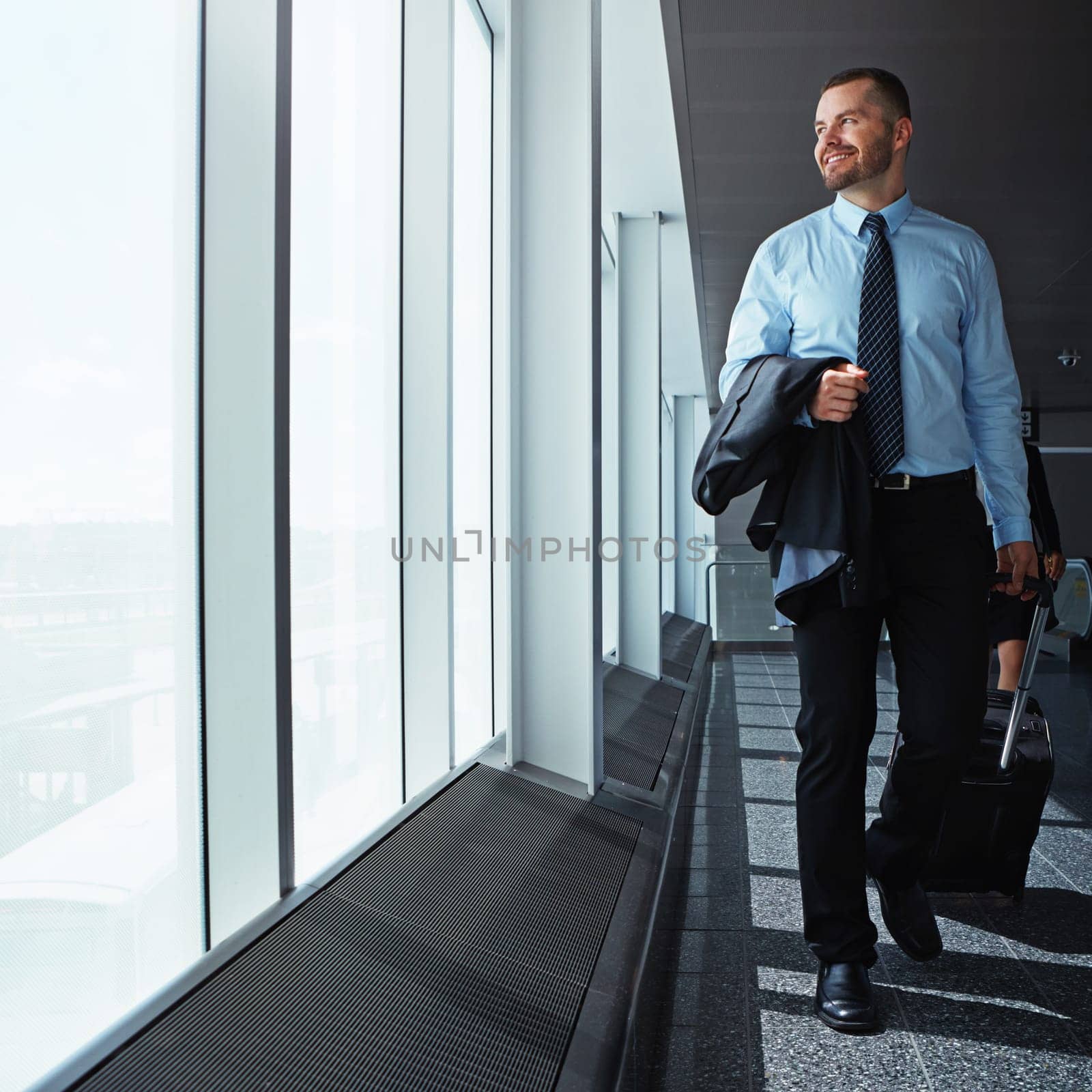 Walking, thinking or happy businessman in airport for a company trip with suitcase or luggage for commute. Smile, window or corporate workers in lobby for travel or journey on international flight by YuriArcurs