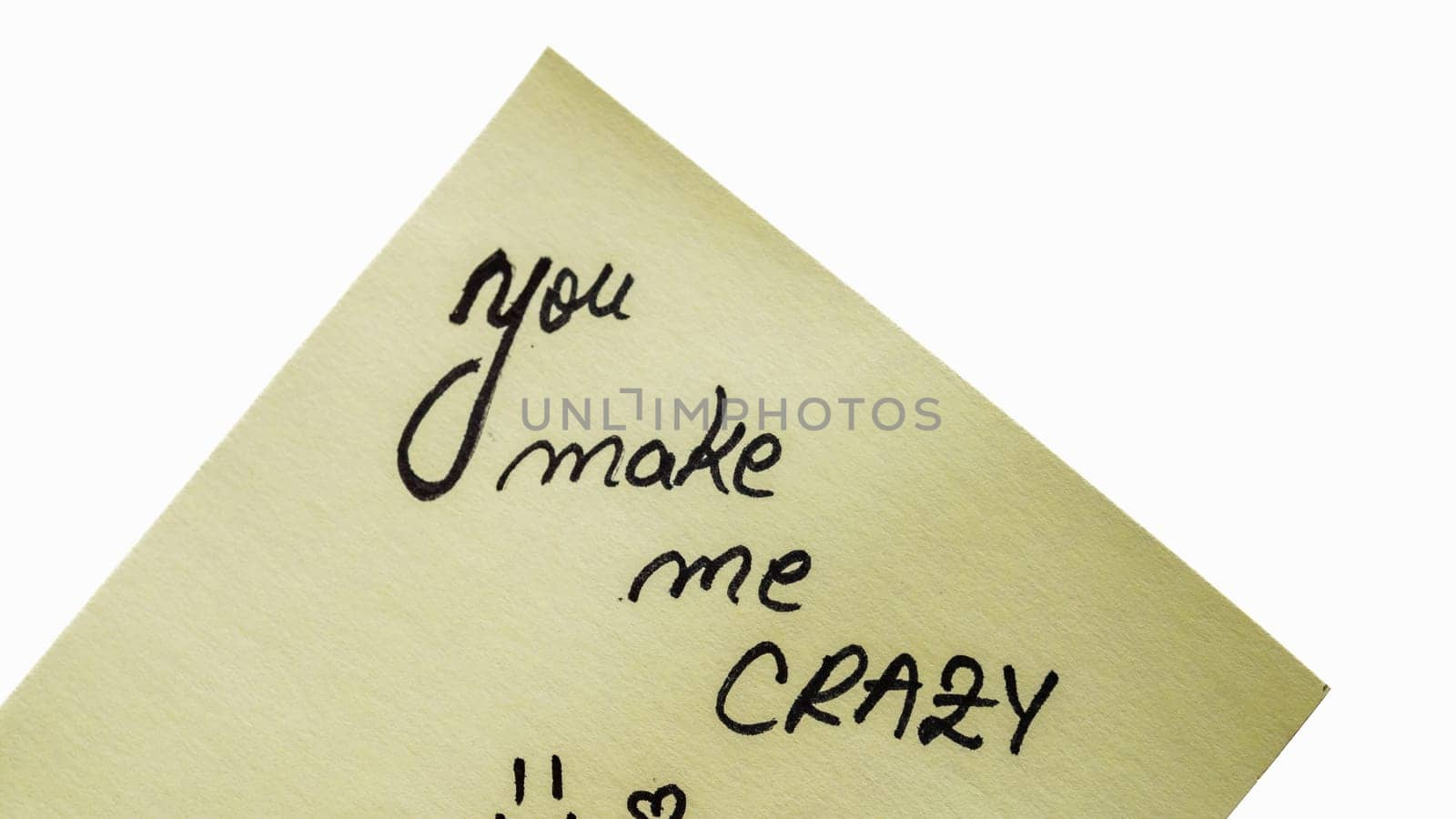 You make me crazy handwriting text close up isolated on yellow paper with copy space. by vladispas