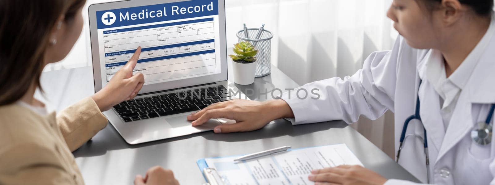 Doctor show medical diagnosis report on laptop and providing compassionate healthcare consultation while being supportive and holding young patient hand in doctor clinic office. Neoteric