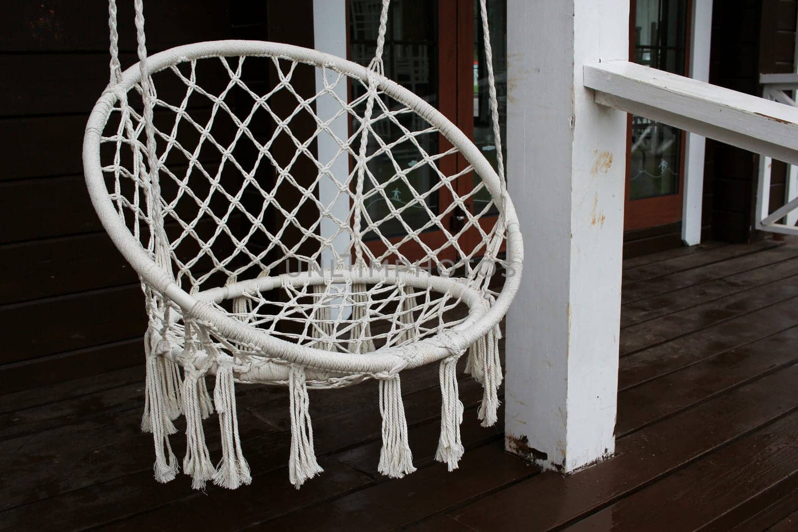 Photo a white hanging swing chair on the veranda. Country life. Comfort and coziness.