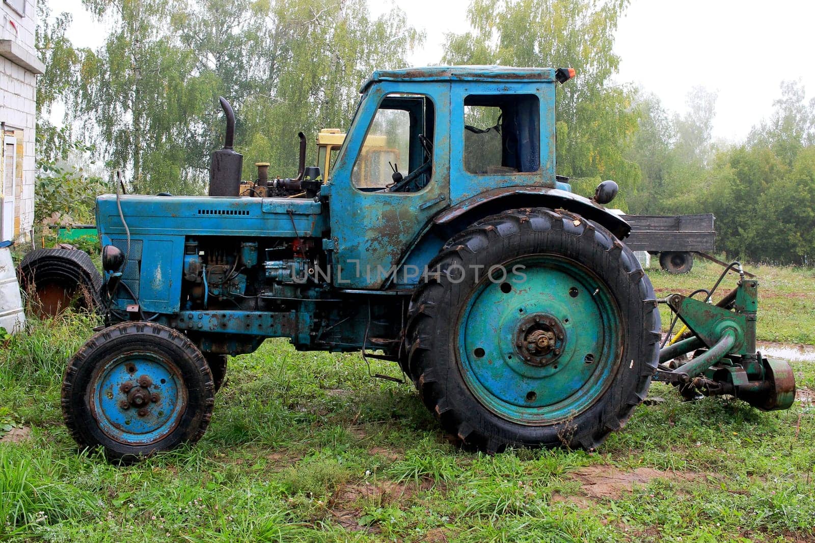 Photo of a blue old tractor on a background of trees. Rural life. Special equipment.