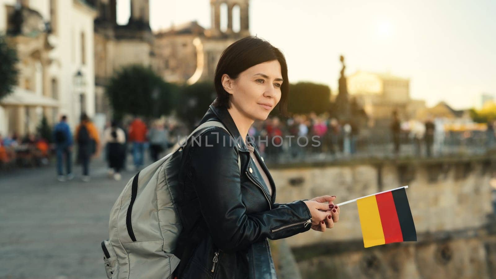 Young Woman Holds German Flag In Hand, With Blurred City Background In Autumn