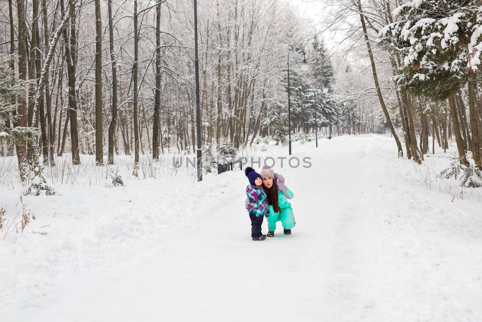 happy family mother and baby girl daughter playing and laughing in winter outdoors in the snow