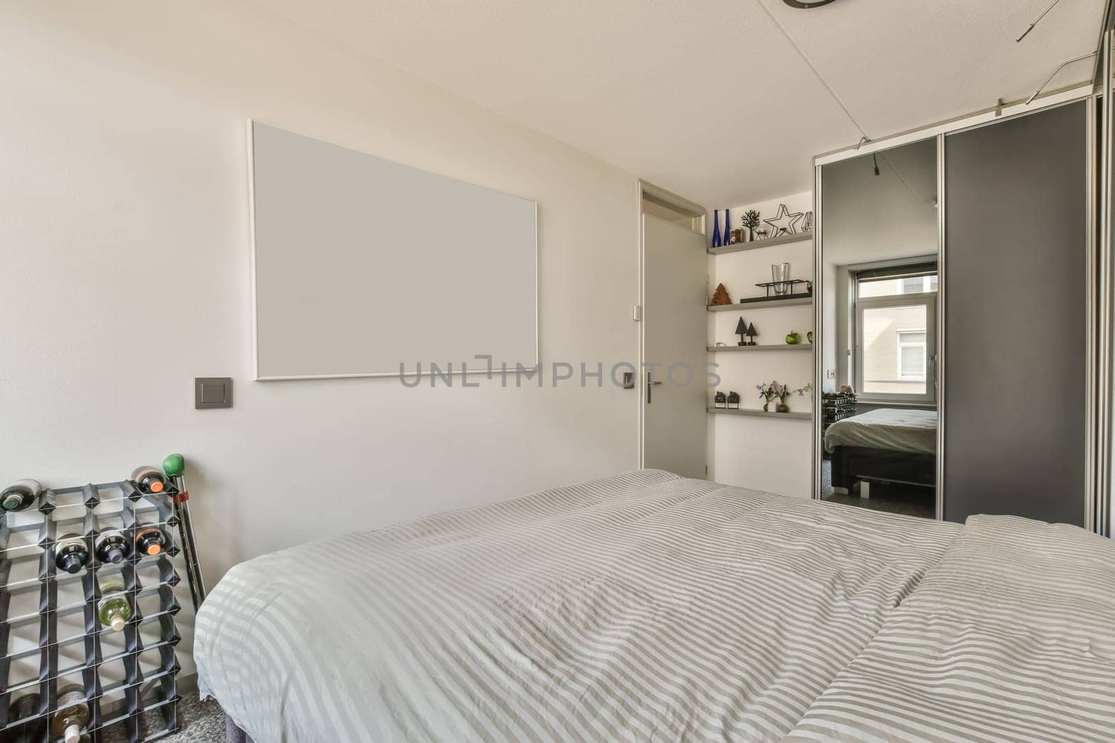 a bedroom with a bed, desk and shelves on the wall behind it is an open door that leads to another room