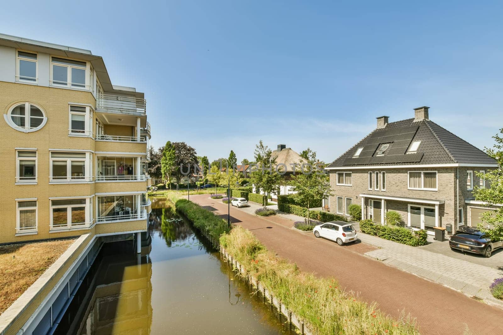 a canal in the middle of a street with houses by casamedia