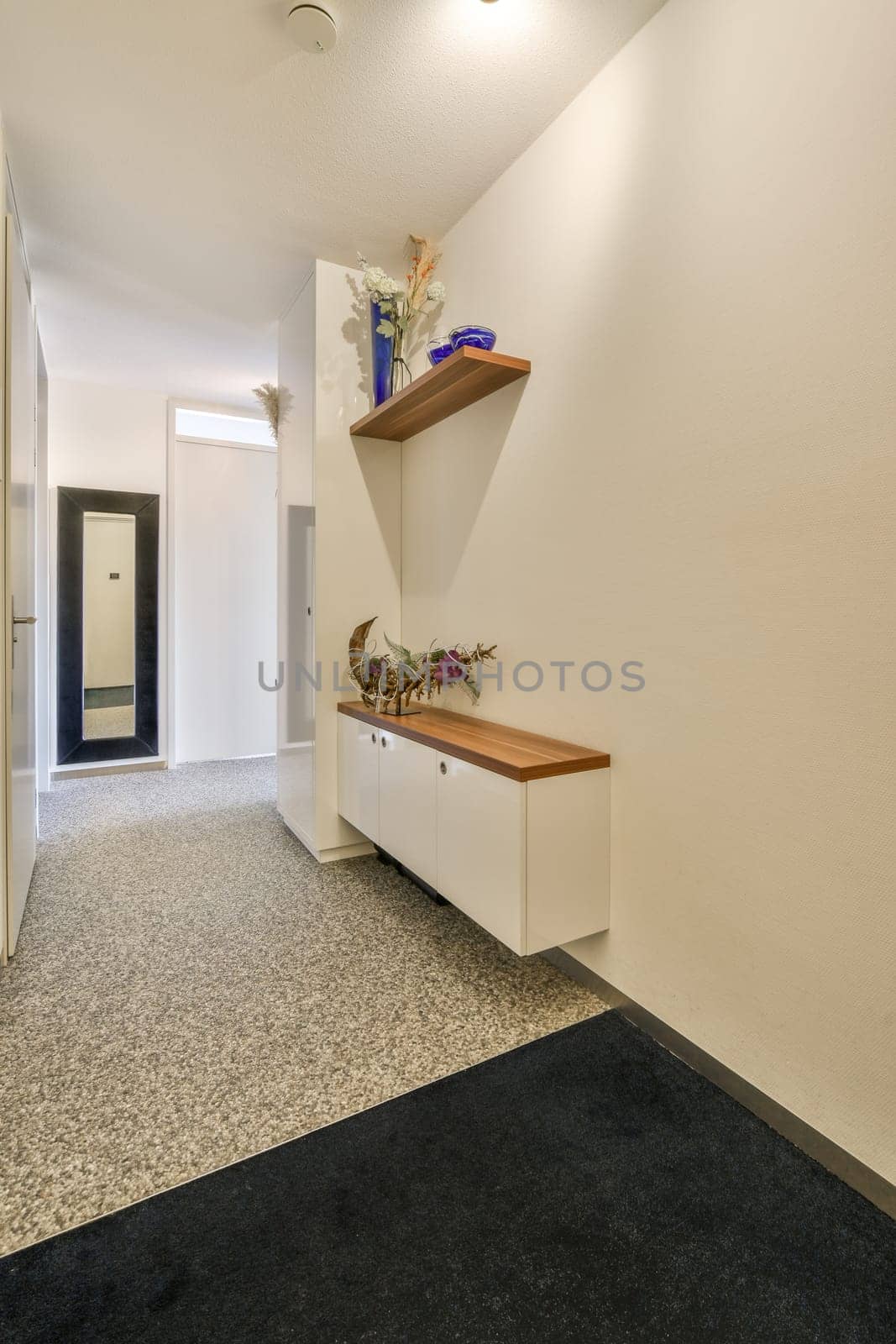 a hallway with some shelves on the wall and flowers in vases sitting on top of cabinetd cupboards