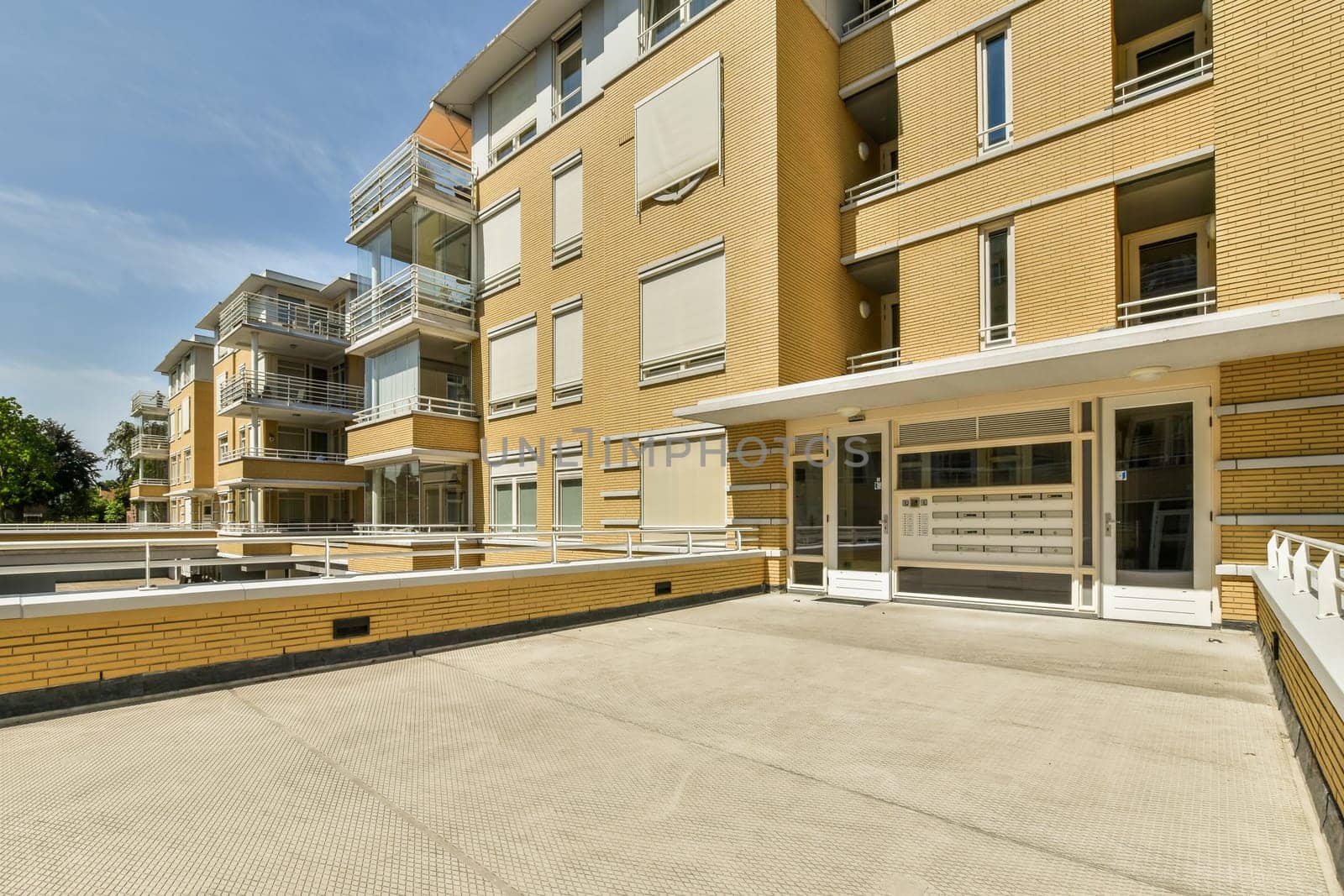 an outside area with some buildings in the background and a white fence on the other side of the building there is a blue sky