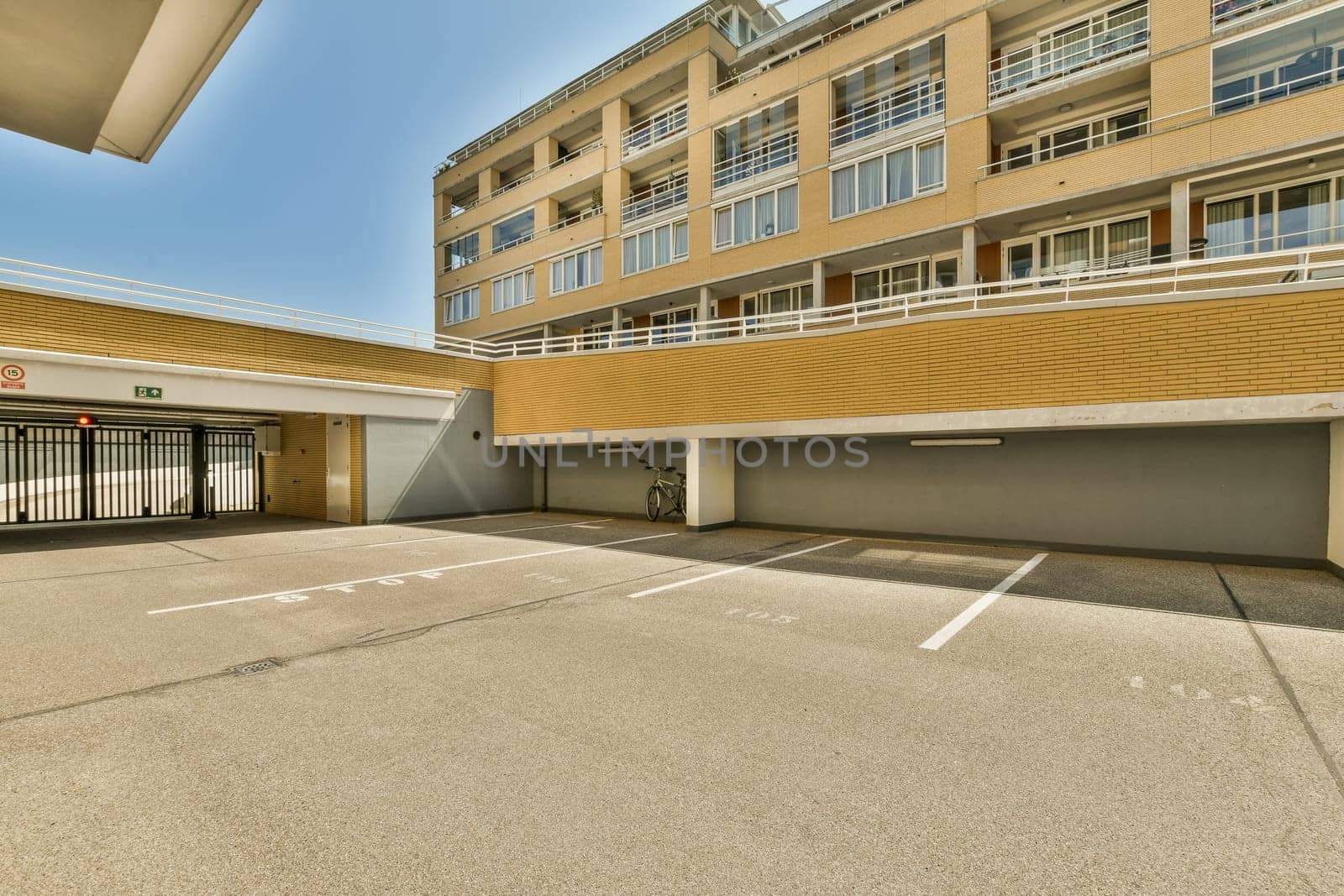 an empty parking area in front of a large brick building with white lines painted on the ground and two garages