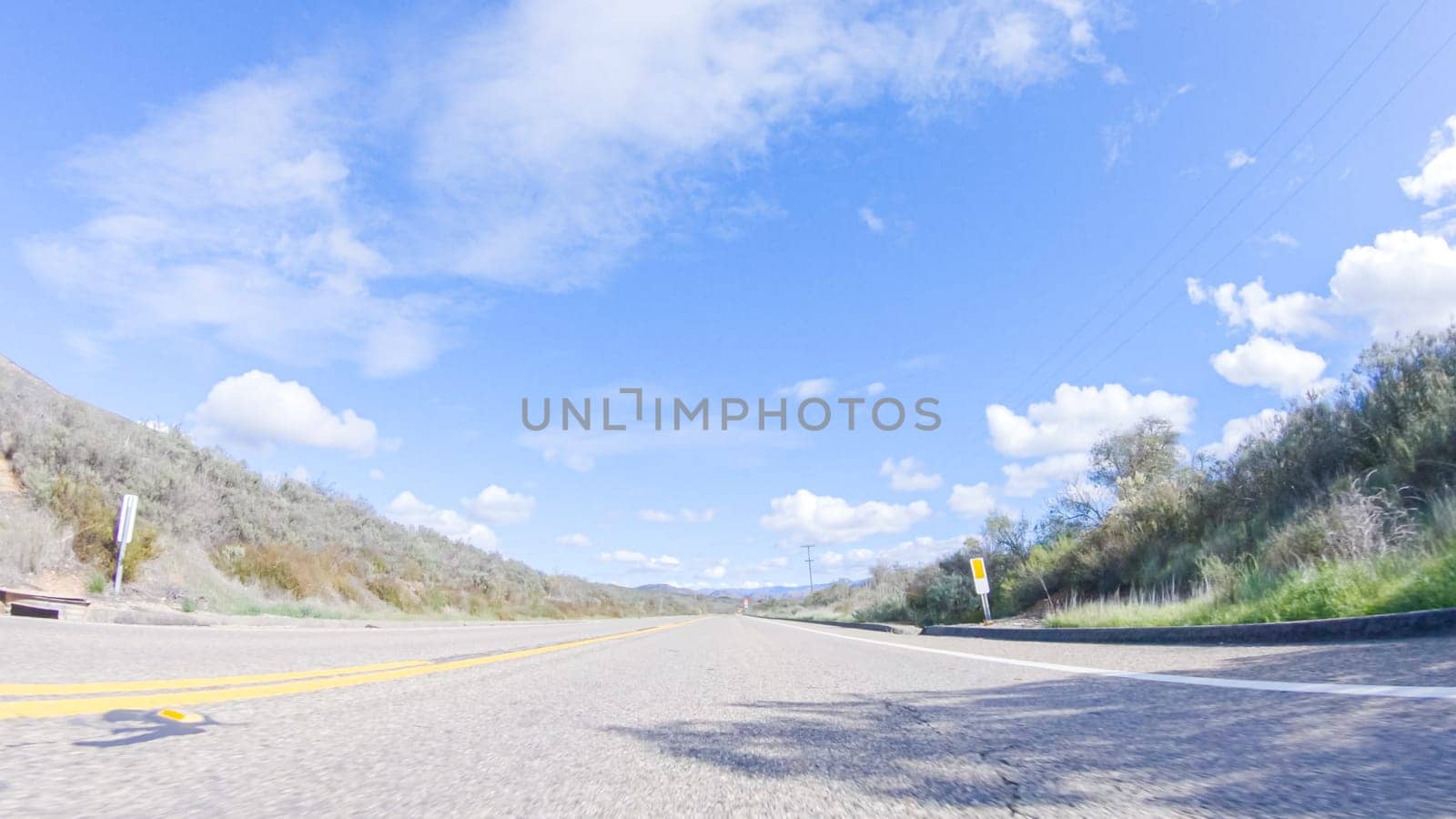 Vehicle is cruising along the Cuyama Highway under the bright sun. The surrounding landscape is illuminated by the radiant sunshine, creating a picturesque and inviting scene as the car travels through this captivating area.