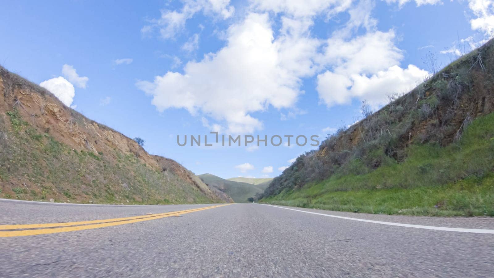 On a clear winter day, a car smoothly travels along Highway 101 near Santa Maria, California, under a brilliant blue sky, surrounded by a blend of greenery and golden hues.