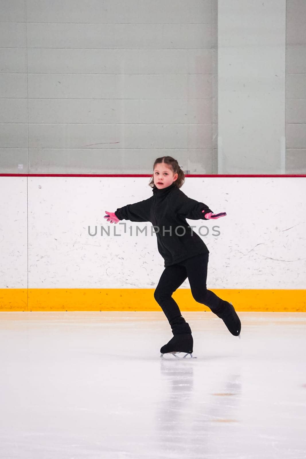 Little girl practicing figure skating at the indoor ice rink.