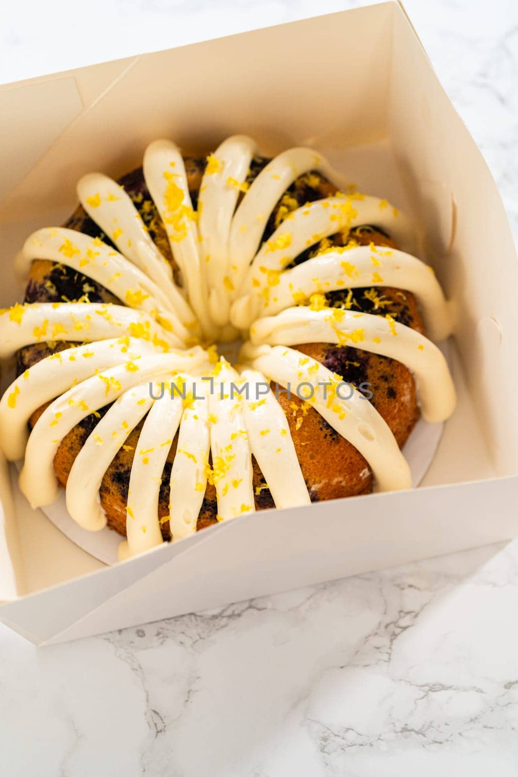 The freshly baked bundt cakes are carefully nestled into white paper boxes, preparing them for secure transportation while maintaining their delectable appearance.