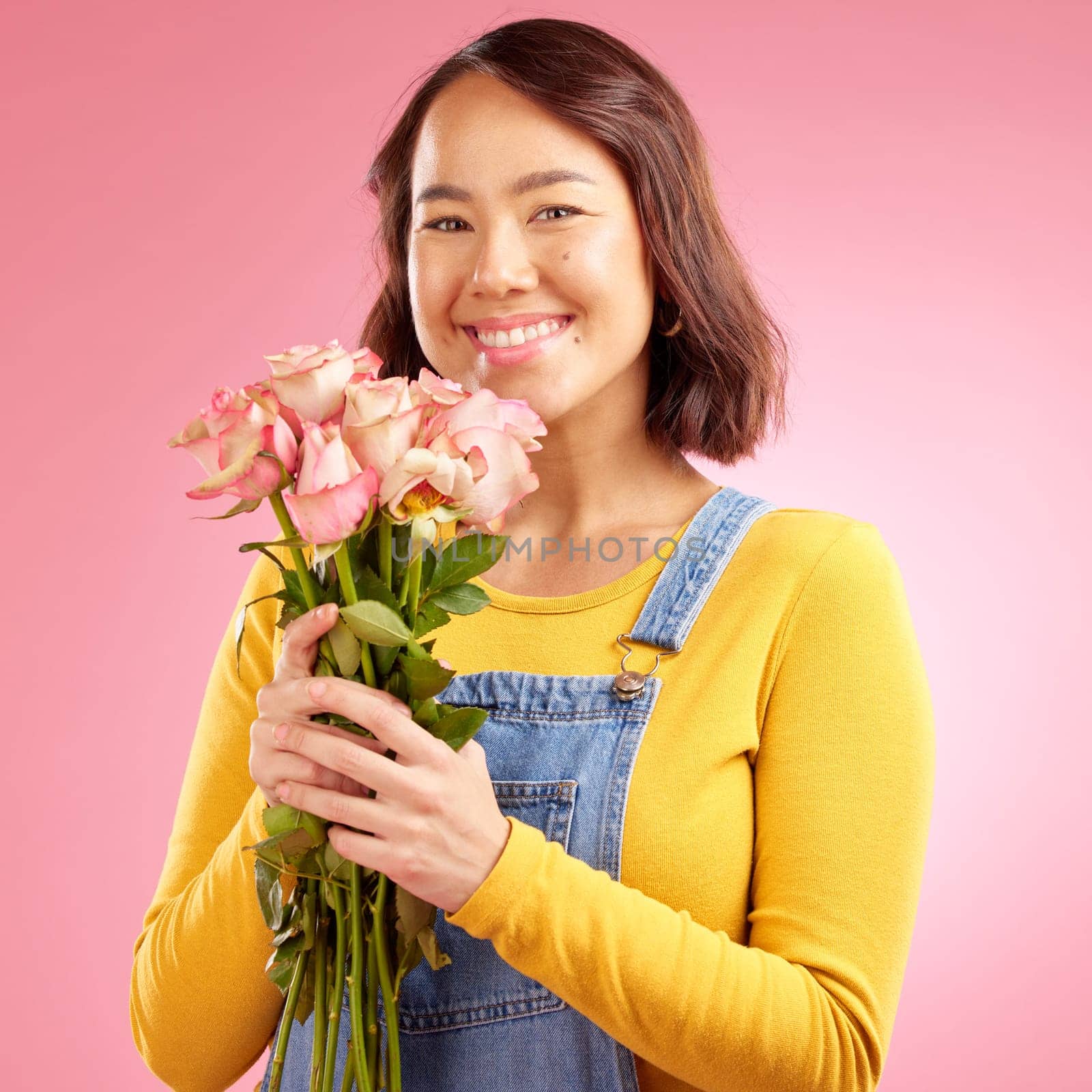 Woman, roses and gift with smile in studio portrait for celebration, birthday or party by pink background. Japanese student girl, gen z fashion and bouquet of flowers for present, reward or romance.