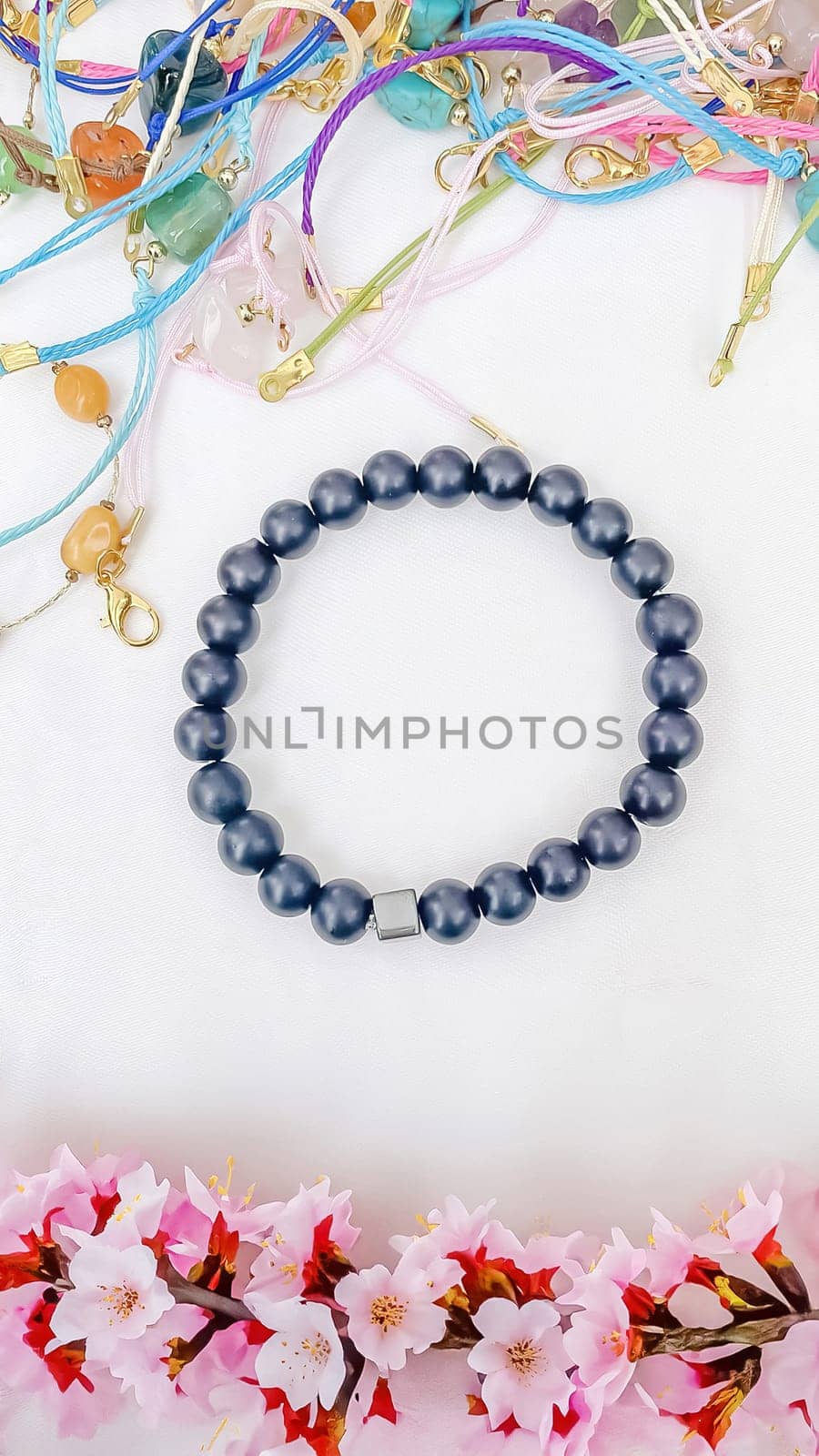 Bracelet of gray stone beads and cherry blossoms on a white background with space for text.