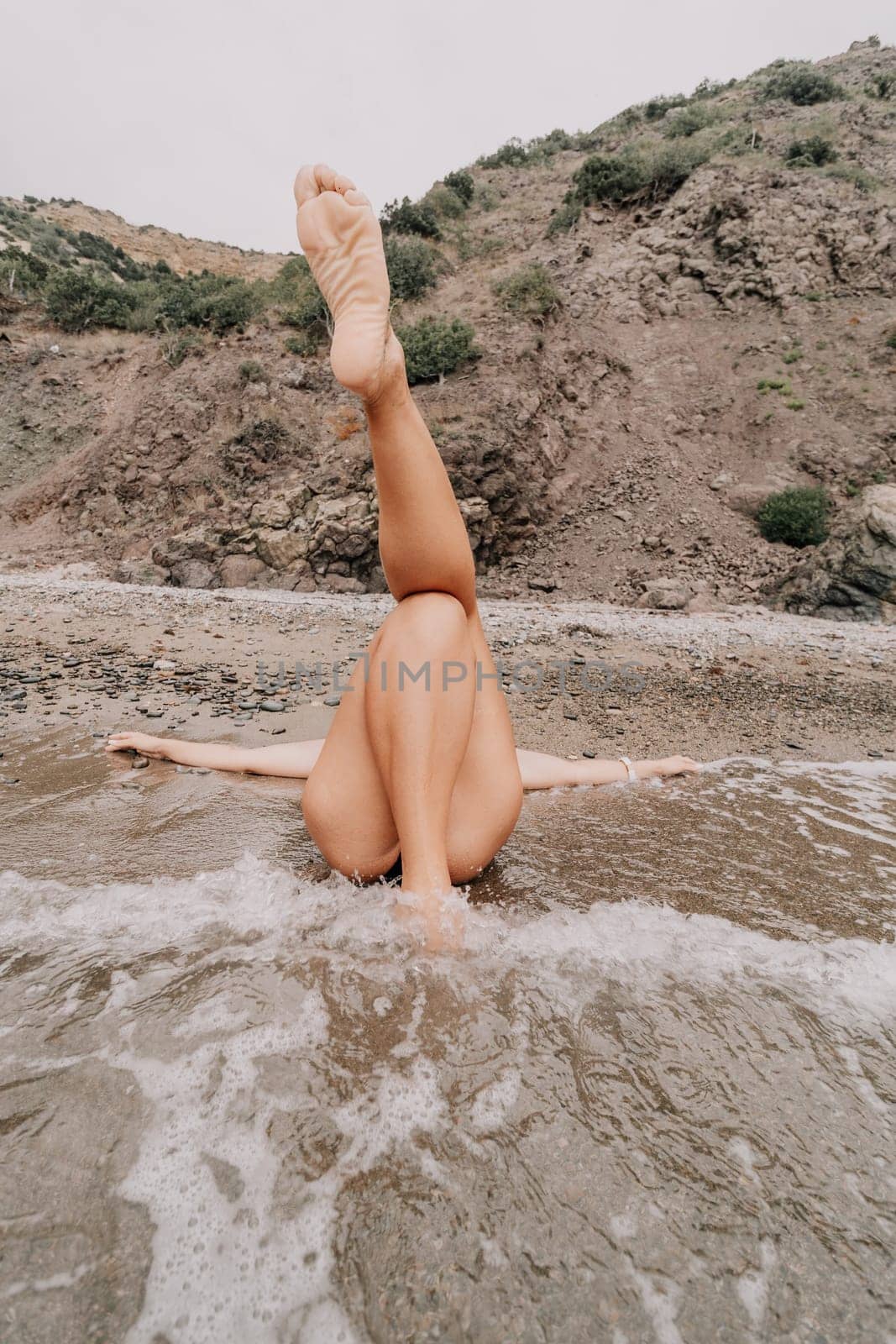 Woman summer travel sea. Happy tourist in blue bikini enjoy taking picture outdoors for memories. Woman traveler posing on the beach surrounded by volcanic mountains, sharing travel adventure journey by panophotograph