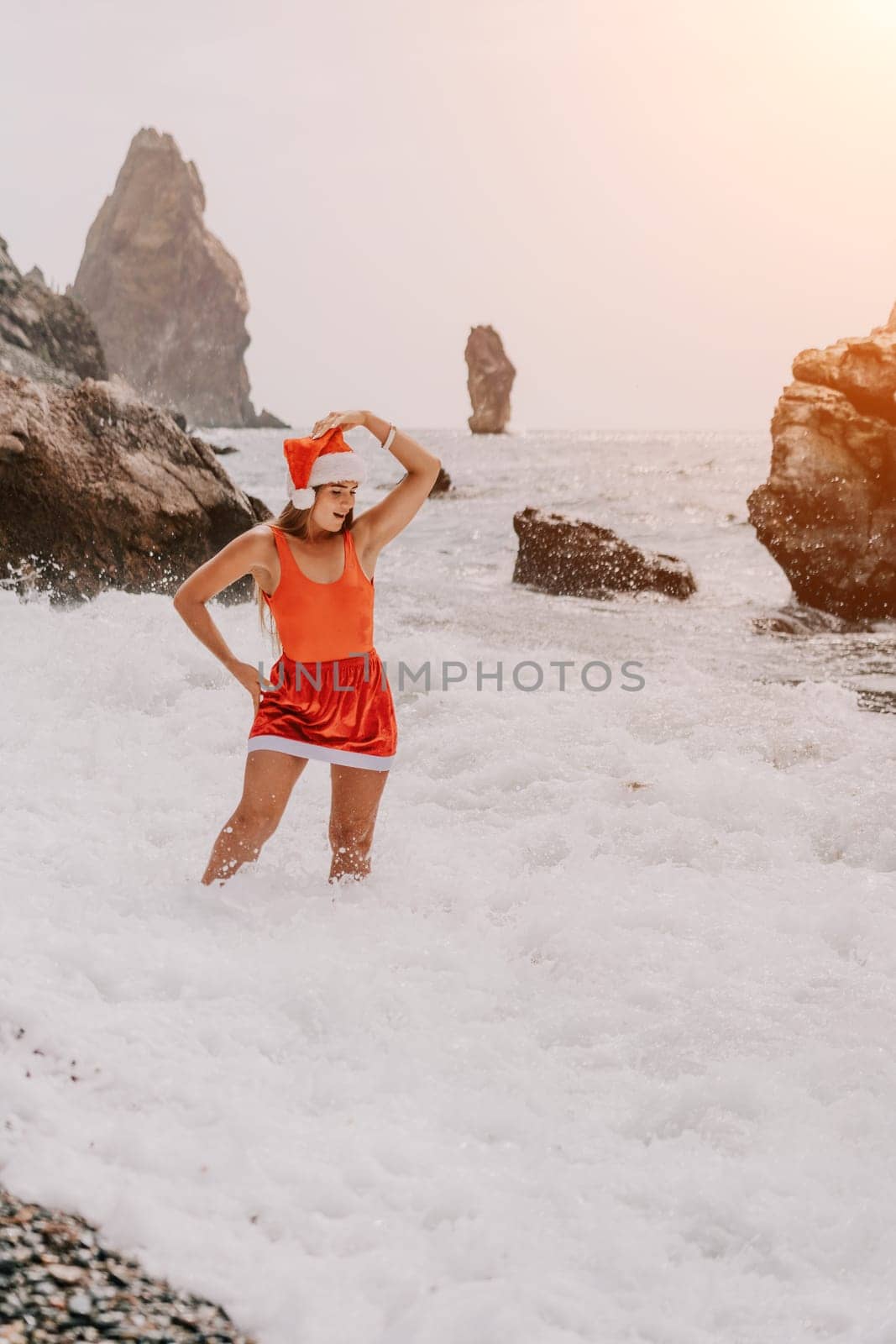 Woman travel sea. Young Happy woman in a long red dress posing on a beach near the sea on background of volcanic rocks, like in Iceland, sharing travel adventure journey