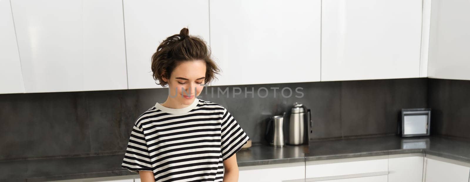 Vertical shot of young smiling woman cooking in the kitchen, chopping vegetables on counter, making healthy meal, vegetarian food.