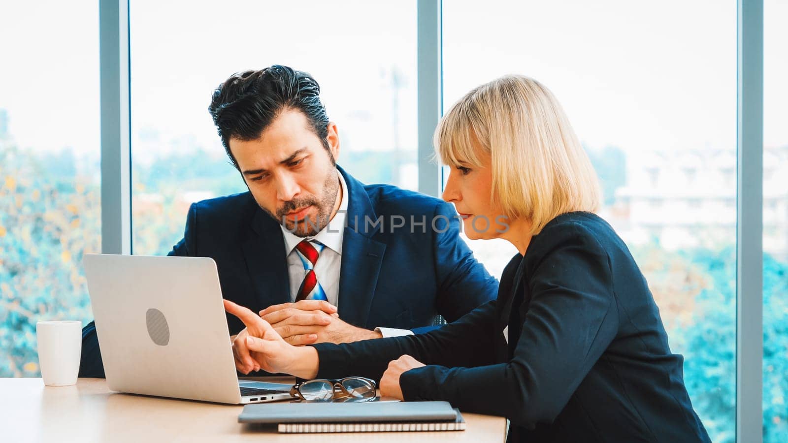 Two business people talk project strategy at office meeting room. Businessman discuss project planning with colleague at modern workplace while having conversation and advice on financial report. Jivy