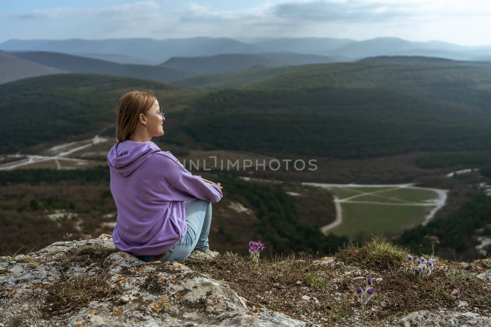 Girl on mountain peak looking at beautiful mountain valley in fog at sunset in summer. Landscape with sporty young woman, foggy hills, forest, sky. Travel and tourism, hiking.