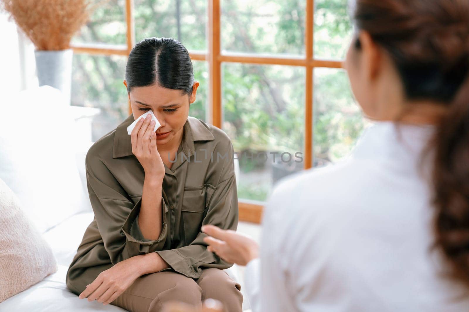 Sad PTSD woman patient in uttermost therapy for mental health with psychologist, depression or grief after life failure. Frustrated trauma young woman talking to a psychologist about emotion in clinic