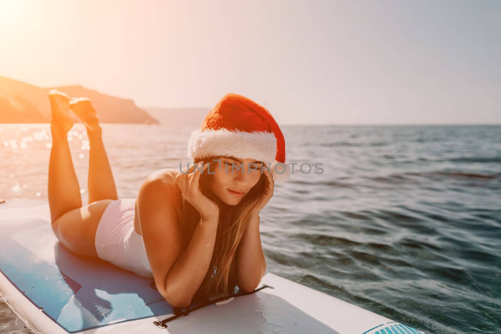 Close up shot of happy young caucasian woman looking at camera and smiling. Cute woman portrait in bikini posing on a volcanic rock high above the sea