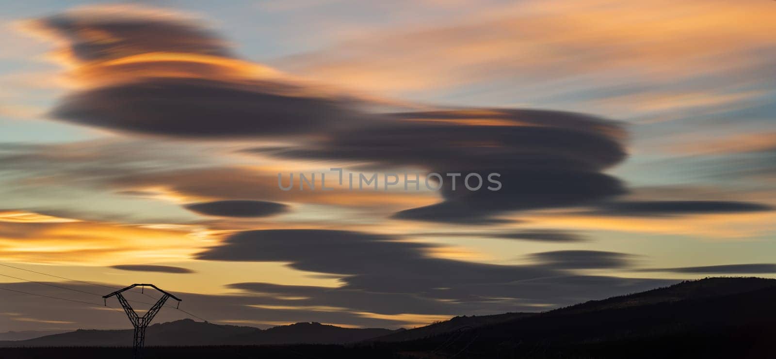 Long Exposure of Electric Towers Silhouettes and Revolving Clouds at Dusk by FerradalFCG