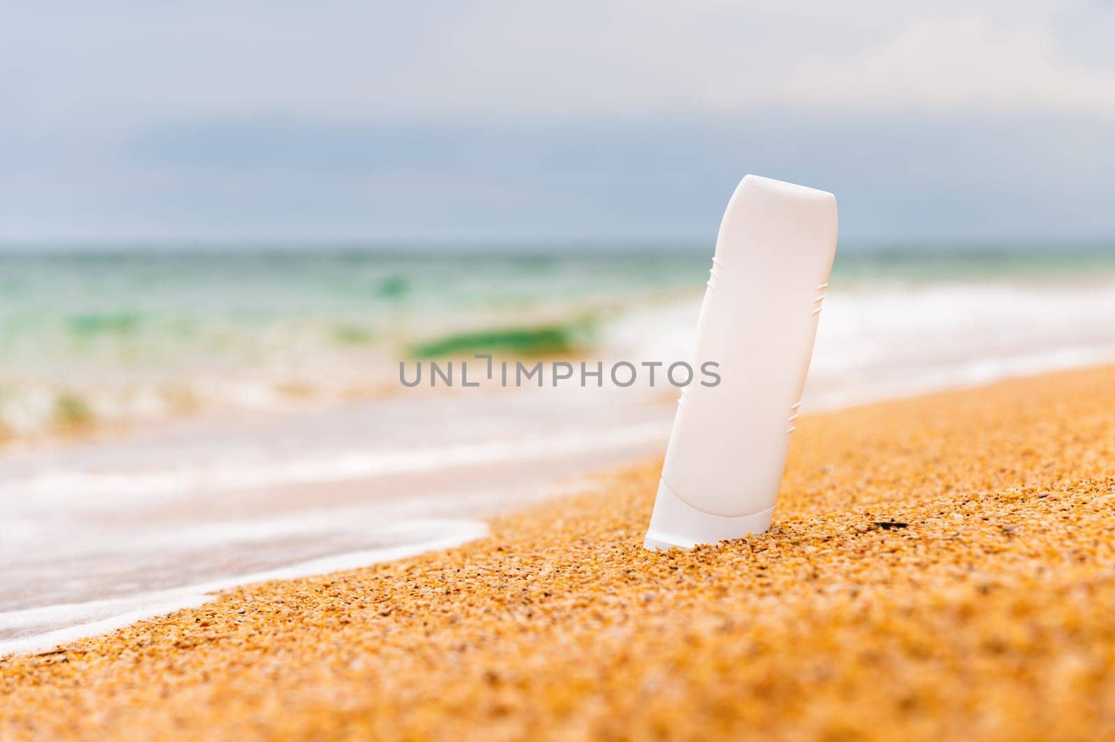 Bottle of sunscreen on the beach. sunburn lotion on the beach with the sparkling sea in the background and rolling waves. Close up of sunscreen cosmetic products by yanik88