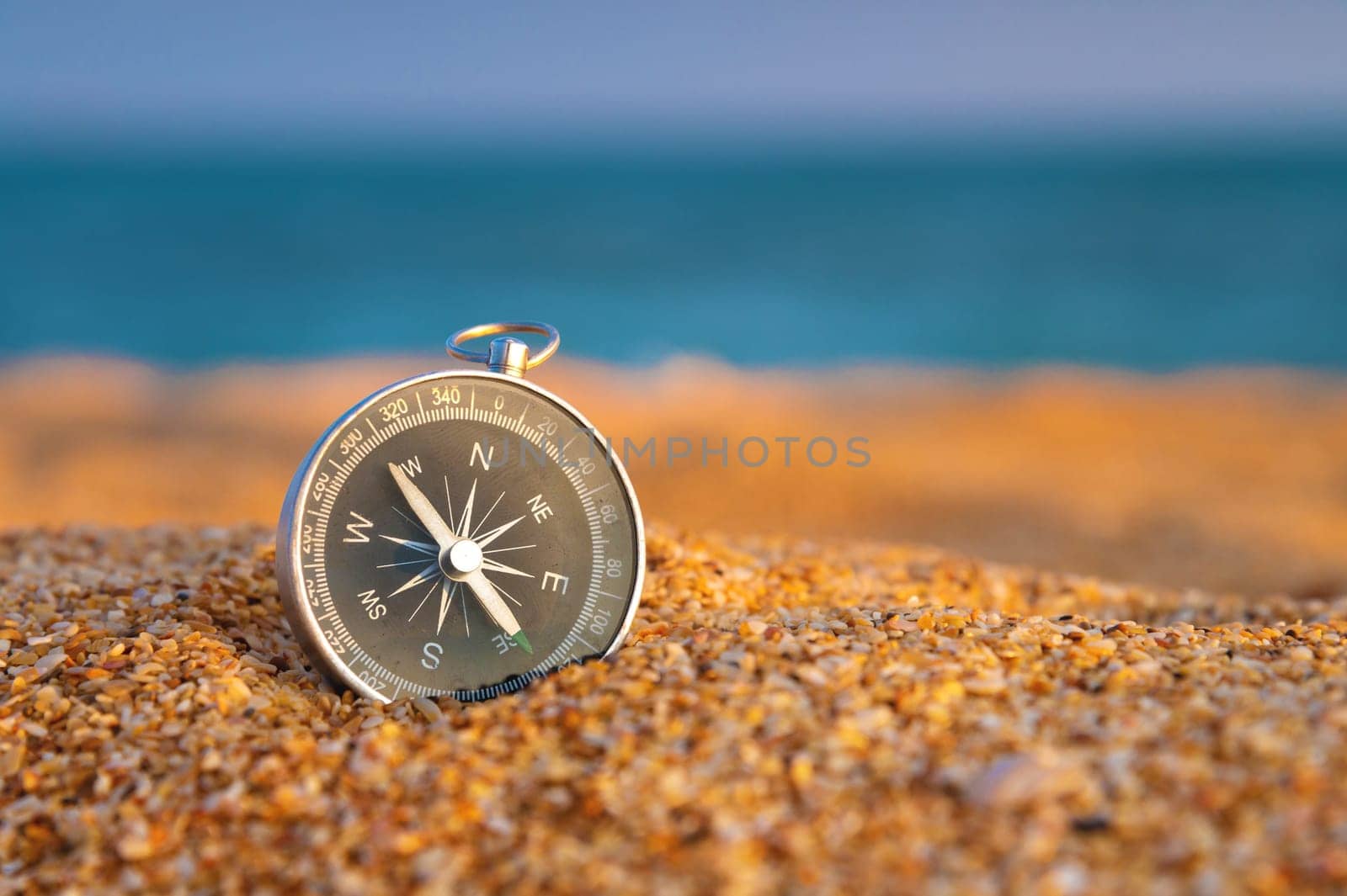 Close up, compass on sand, sea on background in daylight. Finding navigation while traveling along the sea coast by yanik88