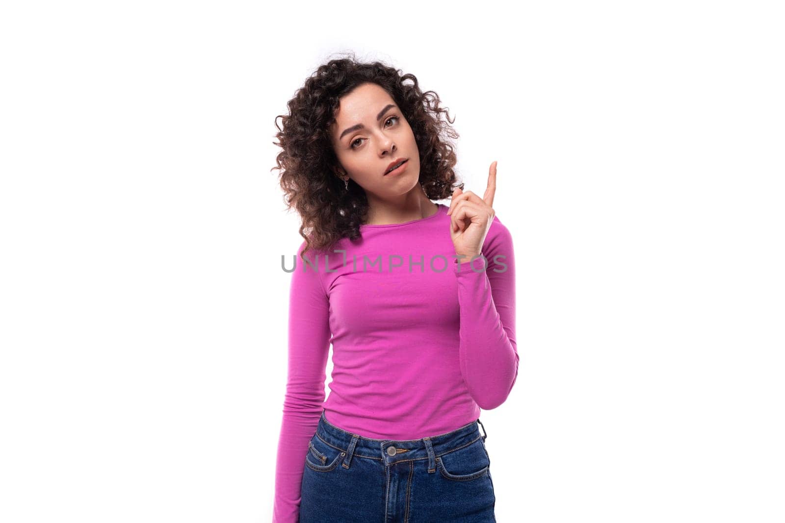 smart thinking young curly brunette woman dressed in purple turtleneck on white background with copy space.