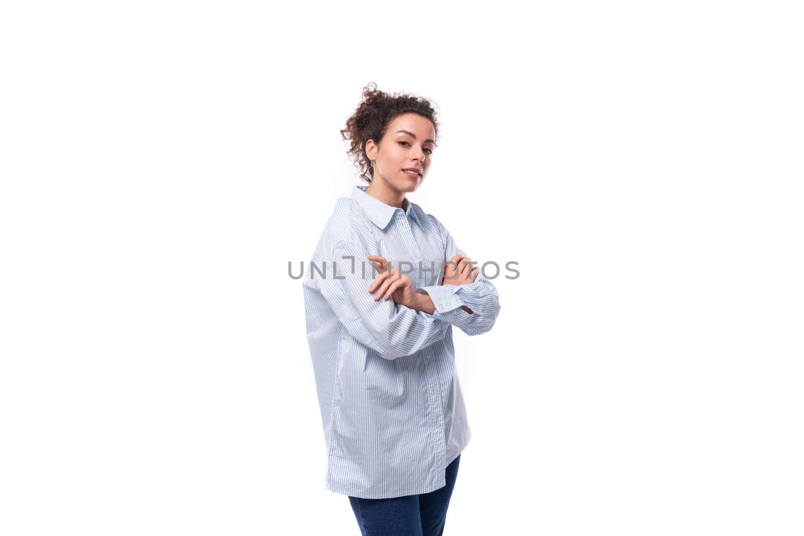 brunette curly young employee of a business company woman dressed in a light blue shirt on a white background with copy space.