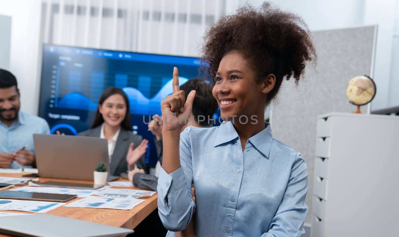 Portrait of happy young african businesswoman with group of office worker on meeting with screen display business dashboard in background. Confident office lady at team meeting. Concord