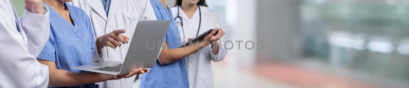 Medical staff team with doctor nurse and specialist working together with laptop and tablet on blur hospital corridor background. Medical and healthcare community in panoramic banner. Neoteric