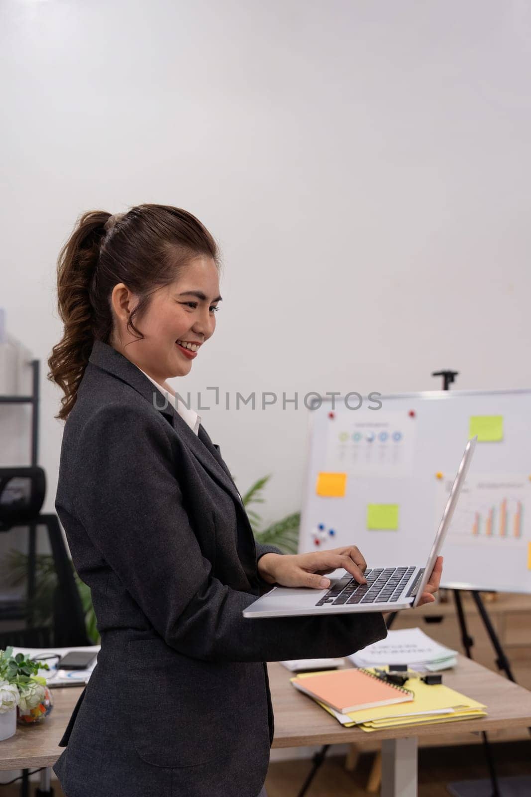 Beautiful young concentration business woman using laptop while standing in office.