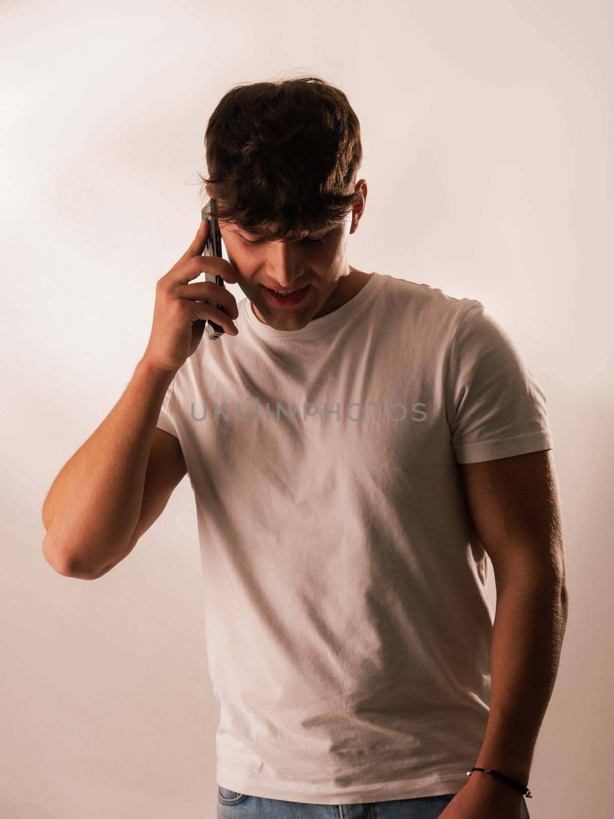 A man in a white shirt talking on a cell phone. Handsome Young Man in a White Shirt Engaged in a Phone Conversation
