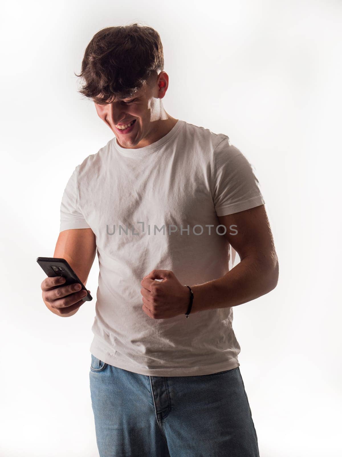 A Joyful Moment Captured: A Handsome Man Laughing With a Cell Phone in a Studio Setting by artofphoto