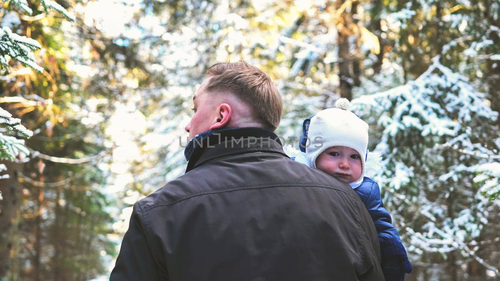 A father and his young son are walking through a winter forest