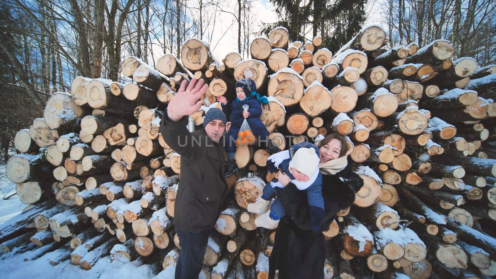 Young family in winter against the background of logs in the woods