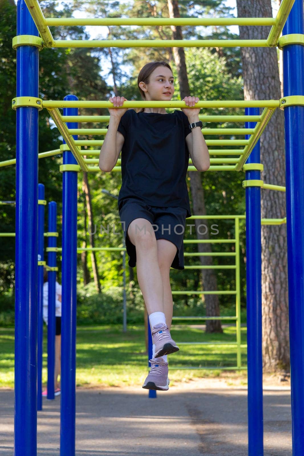 Portrait of beautiful teen age athletic girl training outdoors at open air gym at summer sunny day by BY-_-BY