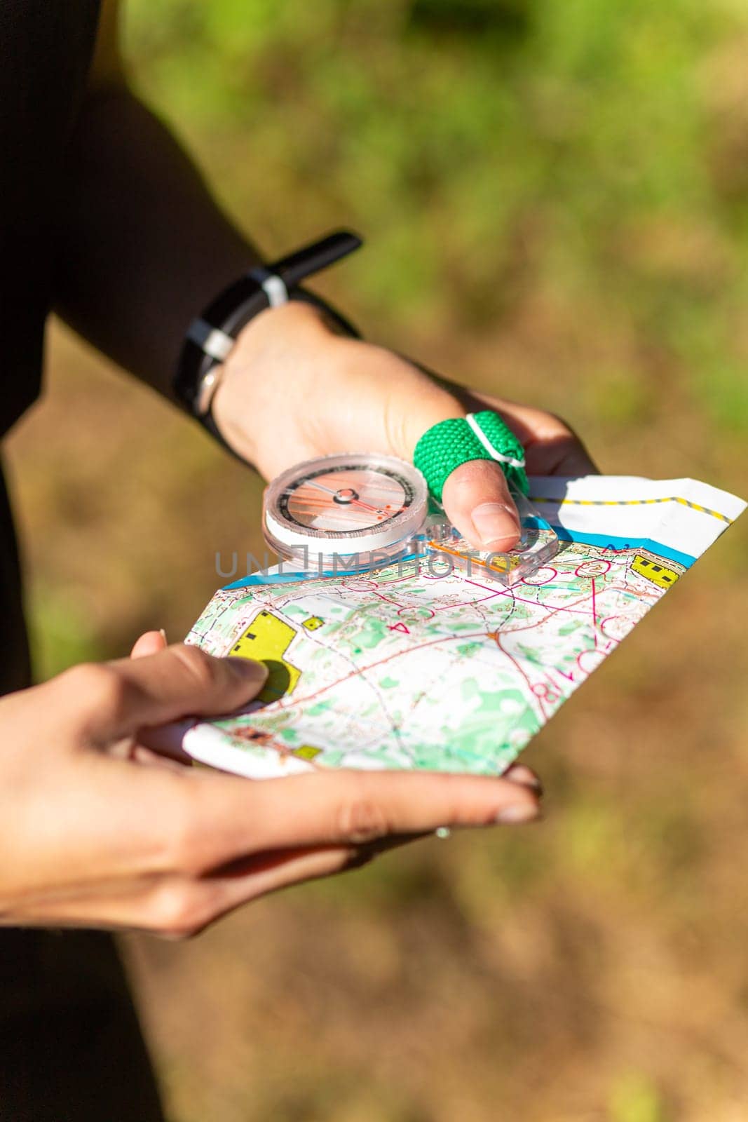 Woman holding a map and the compass during orienteering competitions. by BY-_-BY