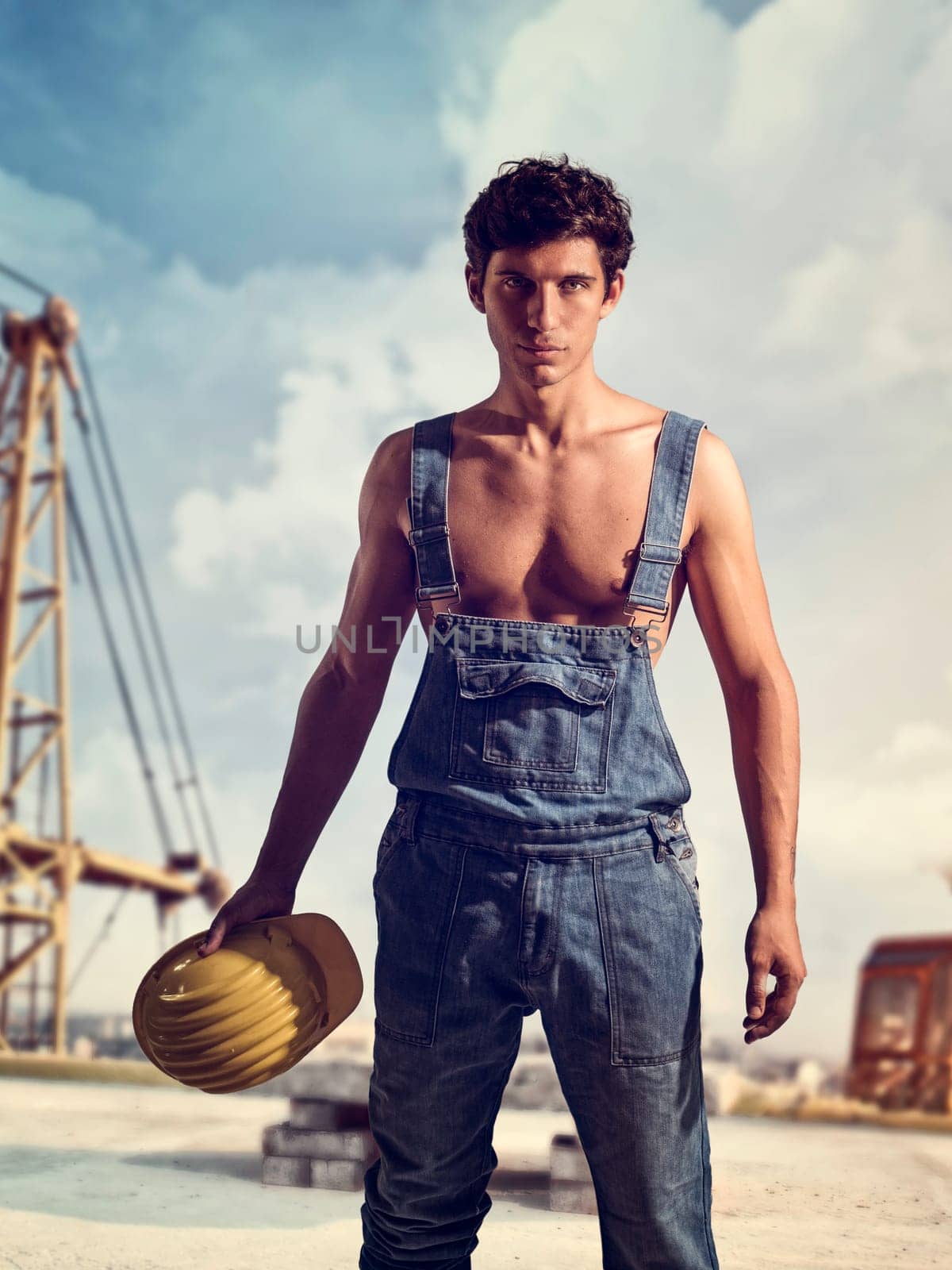 A Handsome Young Man in Overalls Holding a Bucket by artofphoto