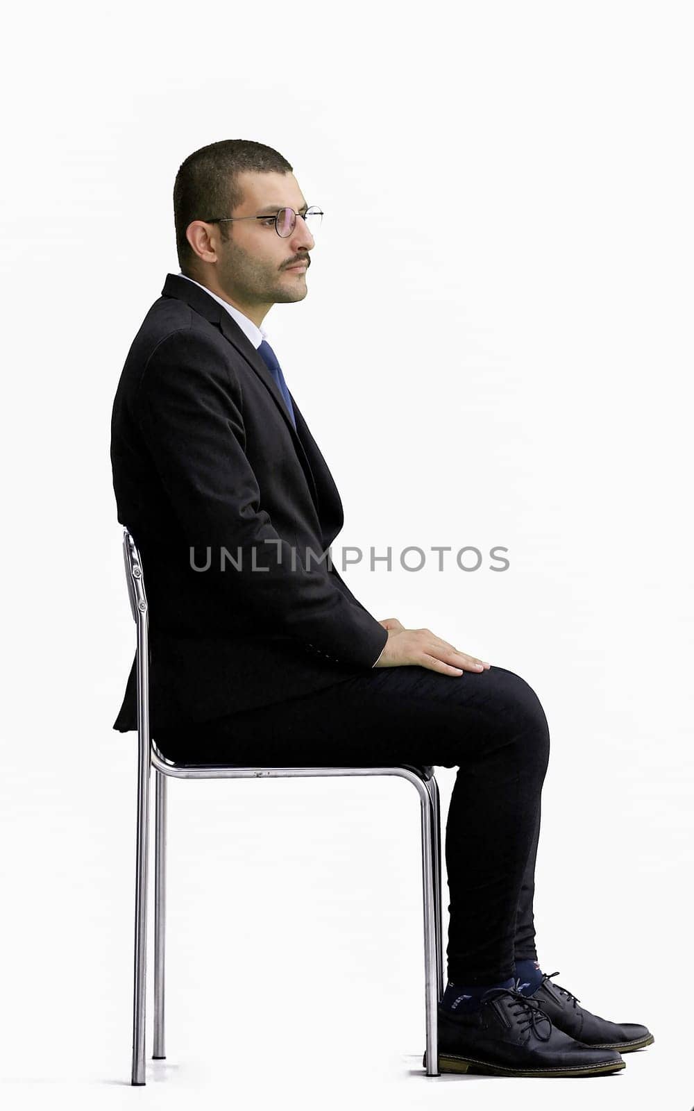 young man in full growth. isolated on a white background sitting on a chair by Prosto