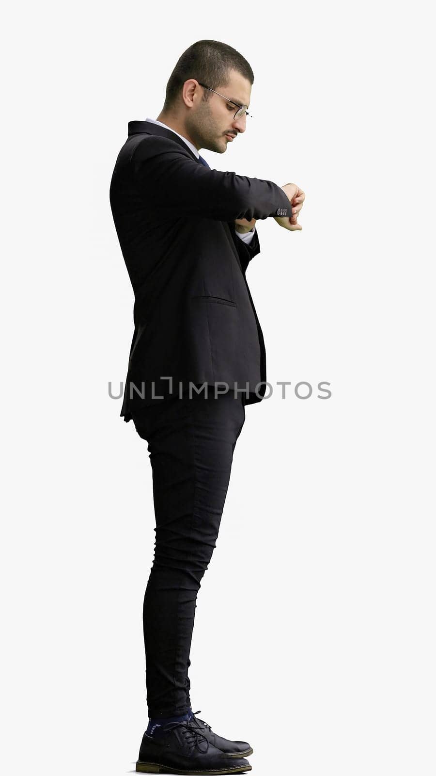 young man in full growth. isolated on white background looking at wristwatch.